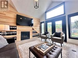 Living room featuring high vaulted ceiling, light hardwood / wood-style flooring, and wood walls - 