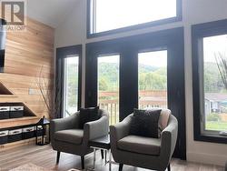 Sitting room featuring high vaulted ceiling, light hardwood / wood-style flooring, and wood walls - 