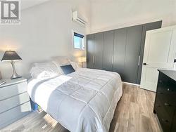 Bedroom featuring light hardwood / wood-style floors, an AC wall unit, and a closet - 