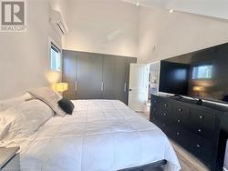 Bedroom featuring a closet, a towering ceiling, a wall mounted air conditioner, and light wood-type flooring - 