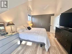 Bedroom featuring light hardwood / wood-style floors, high vaulted ceiling, and a wall mounted AC - 