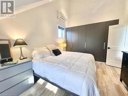 Bedroom featuring a wall mounted AC, a closet, a high ceiling, and light wood-type flooring - 