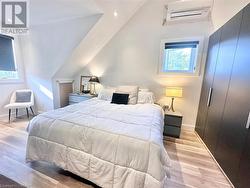 Bedroom with light hardwood / wood-style floors, a wall mounted AC, and lofted ceiling - 