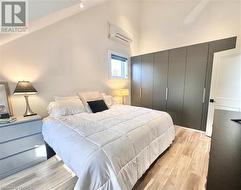 Bedroom featuring a wall unit AC, a closet, vaulted ceiling, and light wood-type flooring - 