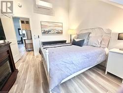 Bedroom featuring an AC wall unit, a high ceiling, and light wood-type flooring - 