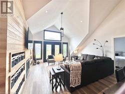 Living room featuring a fireplace, high vaulted ceiling, and wood-type flooring - 