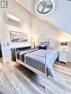 Bedroom featuring ceiling fan, light wood-type flooring, and a wall mounted AC - 