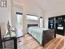 Bedroom with high vaulted ceiling, light wood-type flooring, and a wall unit AC - 