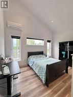 Bedroom featuring multiple windows, light hardwood / wood-style floors, a wall mounted AC, and lofted ceiling - 