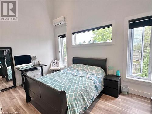 Bedroom featuring light wood-type flooring, an AC wall unit, and multiple windows - 796363 Grey 19 Road, The Blue Mountains, ON - Indoor Photo Showing Bedroom