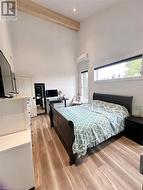 Bedroom featuring beam ceiling, light hardwood / wood-style flooring, and a wall unit AC - 