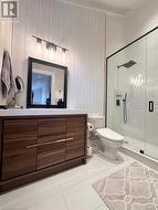 Bathroom featuring tile patterned floors, vanity, toilet, and a shower with door - 