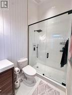 Bathroom with tile patterned floors, vanity, toilet, and a shower with door - 