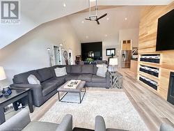 Living room with wooden walls, high vaulted ceiling, and light hardwood / wood-style floors - 