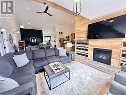 Living room with wooden walls, beam ceiling, light wood-type flooring, and high vaulted ceiling - 