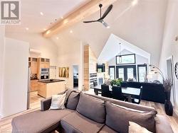 Living room featuring light wood-type flooring, ceiling fan, high vaulted ceiling, an AC wall unit, and beamed ceiling - 