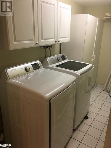 Laundry area featuring cabinets, separate washer and dryer, and light ceramic flooring - 16 Raglan Street E Unit# 211, Collingwood, ON - Indoor Photo Showing Laundry Room