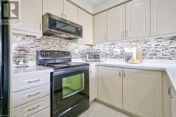 Kitchen featuring black range with electric cooktop and tasteful backsplash - 