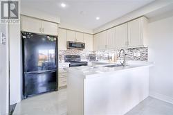 Kitchen with kitchen peninsula, decorative backsplash, sink, and black appliances - 