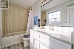 Full bathroom with vanity, hardwood / wood-style flooring, toilet, and shower / bath combo with shower curtain - 