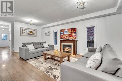 Living room featuring a textured ceiling, light hardwood / wood-style flooring, and a notable chandelier - 48 Isaiah Drive, Kitchener, ON 