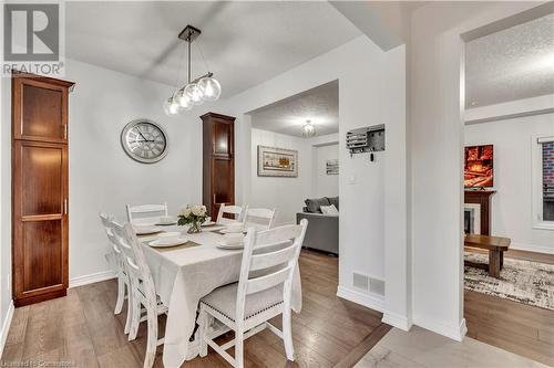 Dining room with a textured ceiling and light hardwood / wood-style flooring - 48 Isaiah Drive, Kitchener, ON 