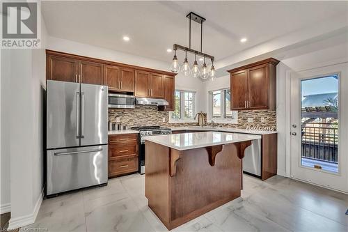 Kitchen with decorative backsplash, a center island, stainless steel appliances, and decorative light fixtures - 48 Isaiah Drive, Kitchener, ON 