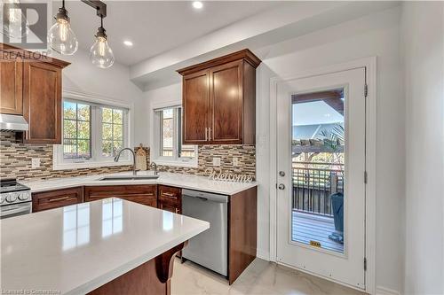 Kitchen with decorative backsplash, sink, pendant lighting, and appliances with stainless steel finishes - 48 Isaiah Drive, Kitchener, ON 