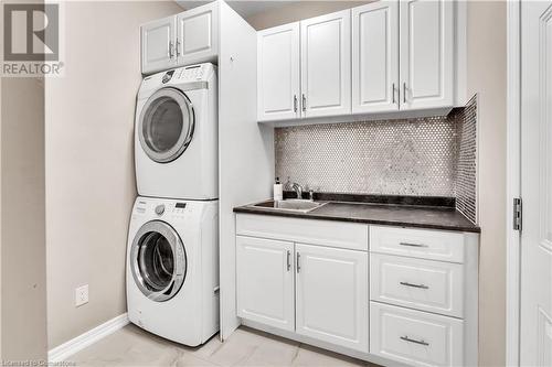 Laundry room with cabinets, sink, and stacked washer and clothes dryer - 48 Isaiah Drive, Kitchener, ON 