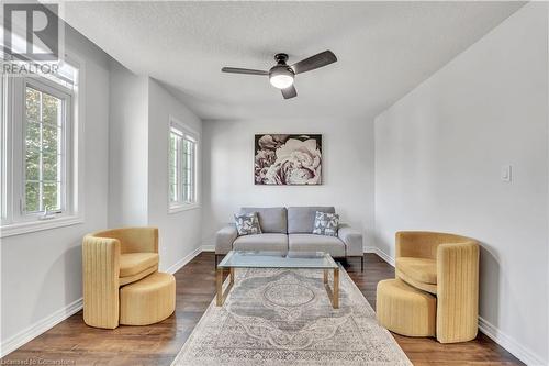 Living room featuring a textured ceiling, ceiling fan, and dark wood-type flooring - 48 Isaiah Drive, Kitchener, ON 