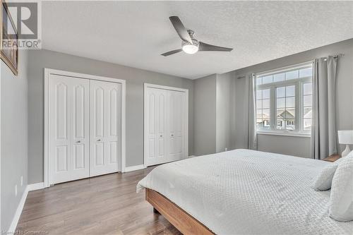 Bedroom featuring multiple closets, ceiling fan, a textured ceiling, and hardwood / wood-style flooring - 48 Isaiah Drive, Kitchener, ON 