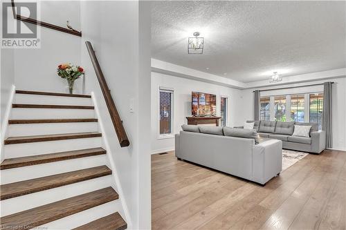 Living room with a textured ceiling and light hardwood / wood-style flooring - 48 Isaiah Drive, Kitchener, ON 