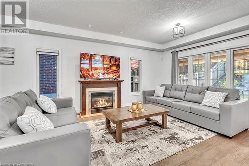 Living room with light wood-type flooring and a textured ceiling - 48 Isaiah Drive, Kitchener, ON 