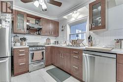 Kitchen featuring backsplash, ceiling fan, ventilation hood, and stainless steel appliances - 