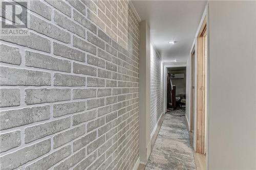 Hallway featuring a wall mounted AC, brick wall, and light wood-type flooring - 476 Prospect Street, Kitchener, ON 