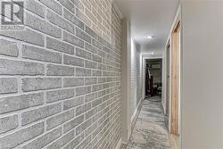 Hallway featuring a wall mounted AC, brick wall, and light wood-type flooring - 