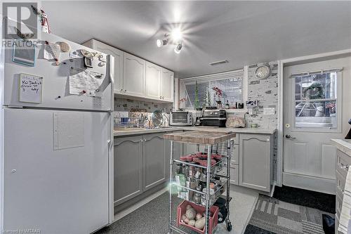 Kitchen with decorative backsplash, white cabinetry, sink, and white fridge - 476 Prospect Street, Kitchener, ON 