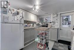 Kitchen with decorative backsplash, white cabinetry, sink, and white fridge - 