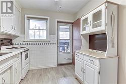 Kitchen with electric stove, white cabinetry, and light wood-type flooring - 