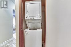 Laundry area featuring stacked washing maching and dryer and hardwood / wood-style flooring - 