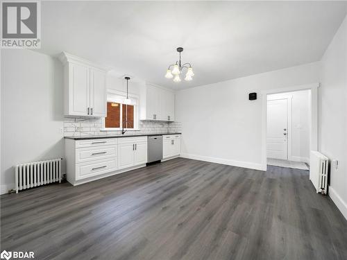 Kitchen featuring radiator heating unit, dark hardwood / wood-style flooring, white cabinetry, and stainless steel dishwasher - 206 Mary Street, Orillia, ON 