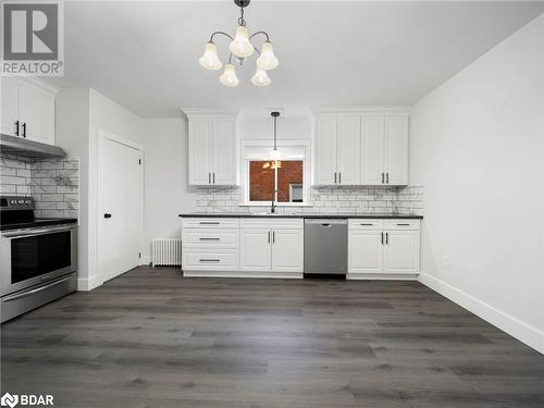 Kitchen featuring white cabinets, radiator heating unit, stainless steel appliances, and dark wood-type flooring - 206 Mary Street, Orillia, ON 