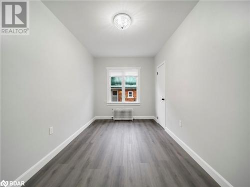 Empty room featuring radiator and dark hardwood / wood-style floors - 206 Mary Street, Orillia, ON 