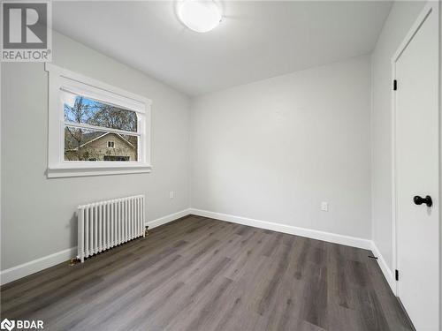 Unfurnished bedroom featuring radiator heating unit and dark hardwood / wood-style floors - 206 Mary Street, Orillia, ON 