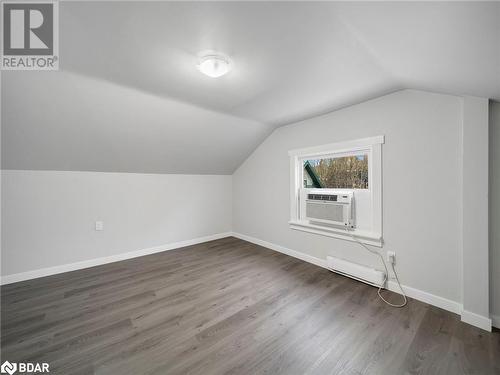 Additional living space with dark hardwood / wood-style floors, vaulted ceiling, cooling unit, and a baseboard radiator - 206 Mary Street, Orillia, ON 