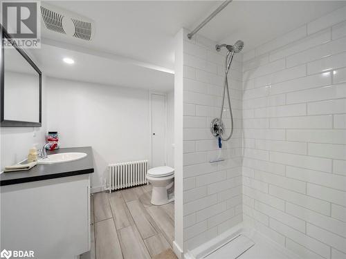 Bathroom with a tile shower, radiator heating unit, vanity, and wood-type flooring - 206 Mary Street, Orillia, ON 