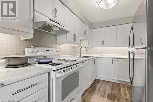 Kitchen with white range with electric stovetop, stainless steel refrigerator, white cabinetry, and sink - 9 Bonheur Court Unit# 802, Brantford, ON 