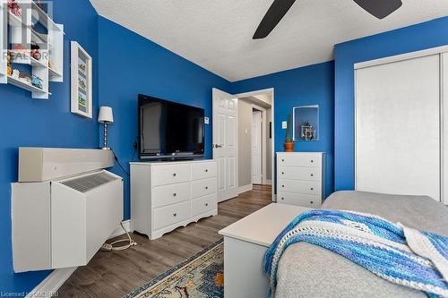 Bedroom featuring ceiling fan, dark hardwood / wood-style flooring, a textured ceiling, and a closet - 9 Bonheur Court Unit# 802, Brantford, ON 