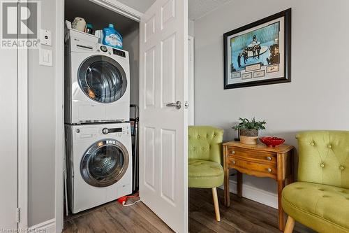 Washroom featuring a textured ceiling, dark hardwood / wood-style floors, and stacked washer / dryer - 9 Bonheur Court Unit# 802, Brantford, ON 