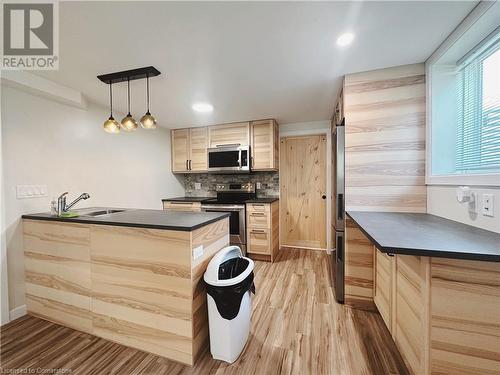 Kitchen with sink, stainless steel appliances, light hardwood / wood-style floors, pendant lighting, and light brown cabinetry - 20 Pintail Place, Cambridge, ON 